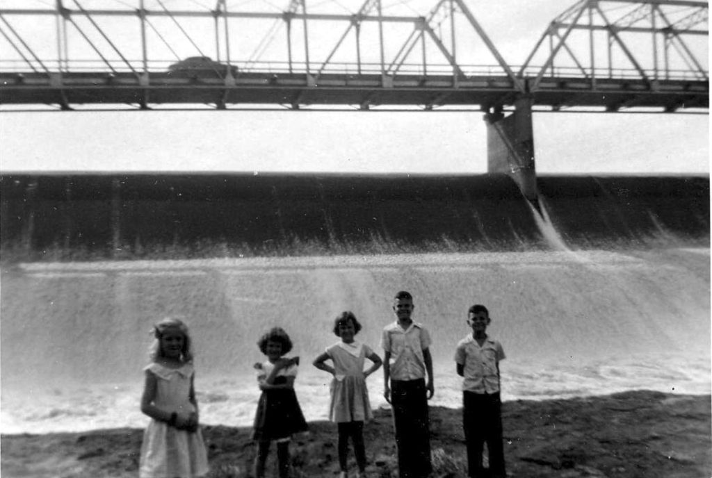 A group of children plays below the Garza-Little Elm Dam and spillway on Lake Dallas. This area would become part of Lewisville Lake just a few years later.